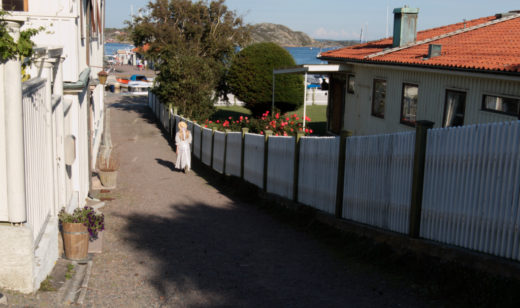 vacker gata i nedförsbacke Marstrand, nerför den går en vackert klädd tjej